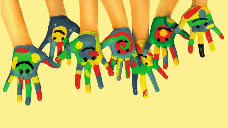 Bunt bemalte Kinderhände mit lachenden Smileys